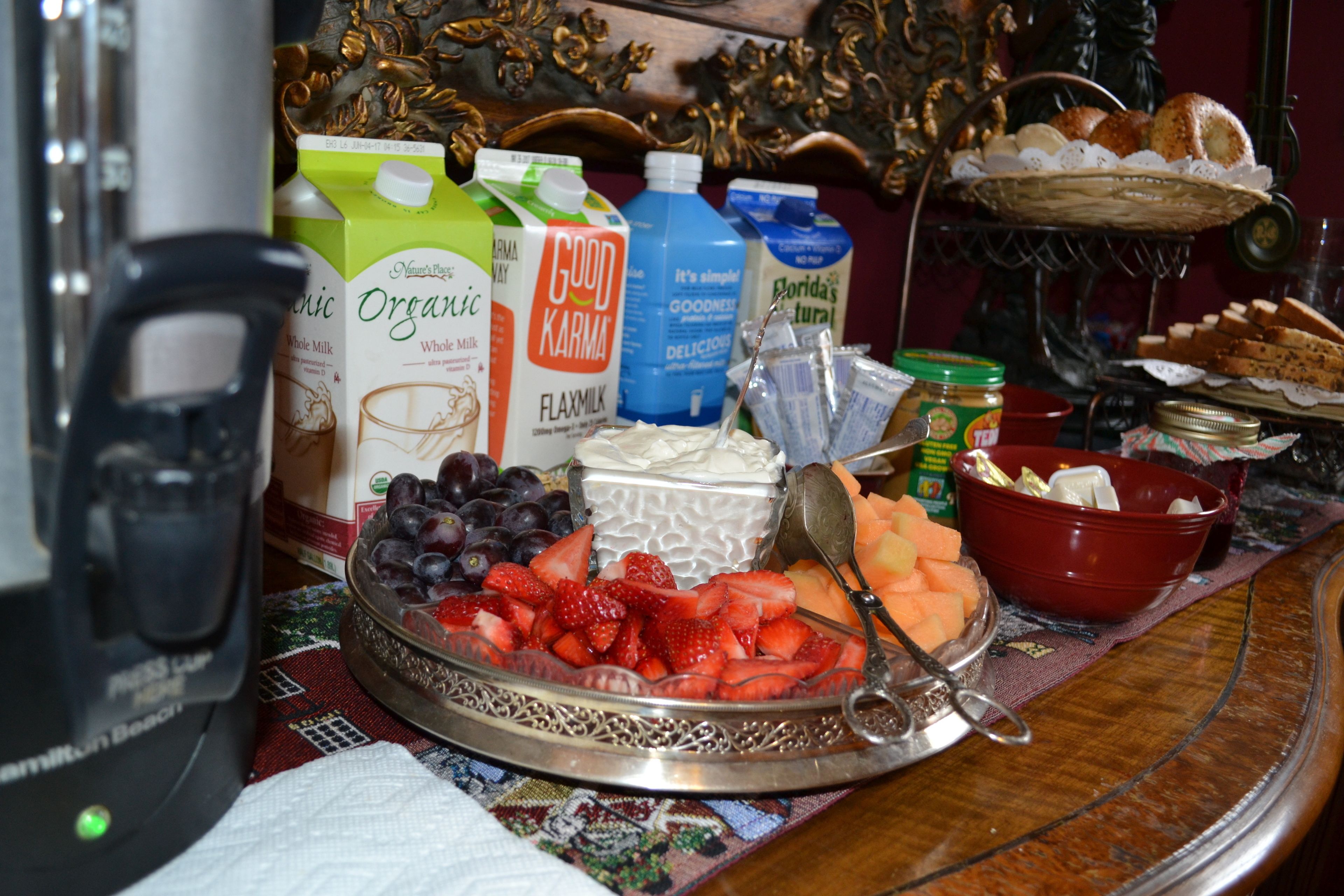 A breakfast table with various food items, including fruits, bread, and dairy products.