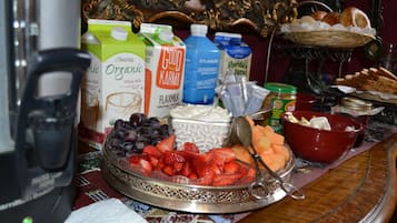 A breakfast table with various food items, including fruits, bread, and dairy products.