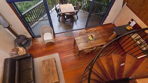 Ein modernes Interieur mit Holzboden, einer Wendeltreppe, einem Essbereich mit Tisch und Stühlen sowie einer Sitzecke mit Sofa und kleinem Tisch.