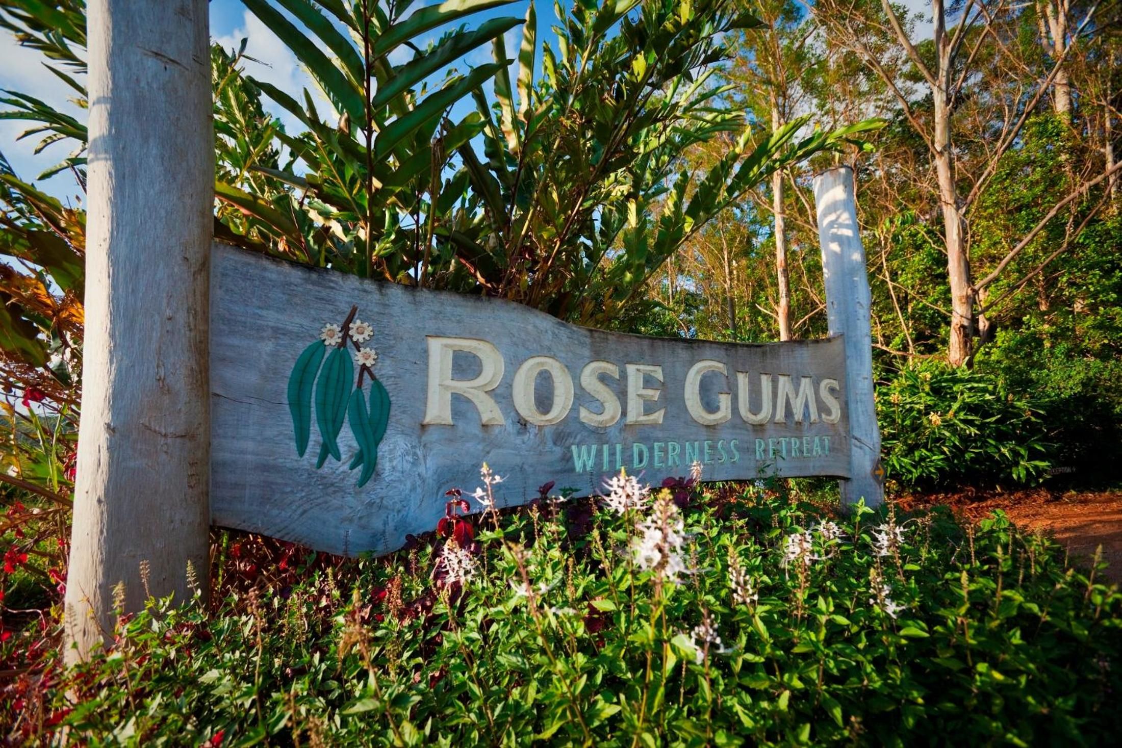 A wooden sign with the text 'ROSE GUMS WILDERNESS RETREAT' and a depiction of a gum tree.