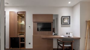 A compact hotel room with a built-in desk, a television, a chair, and a wardrobe with a mirror. - Green World Mai - NanJing (Taipei)