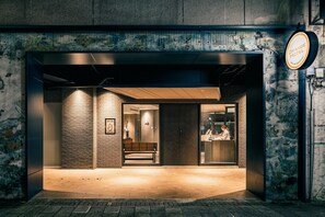 A hotel entrance with a bench outside, a reception desk inside, and a wall with a mural. - Orange Hotel - Ximen (Taipei)