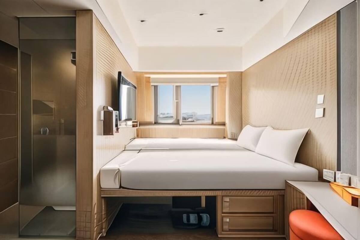 A modern hotel room with a large bed, a desk, and a view of the city.