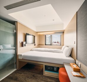 A modern hotel room with a bed, a desk, a TV, and a window with a city view. - Orange Hotel - Ximen (Taipei)