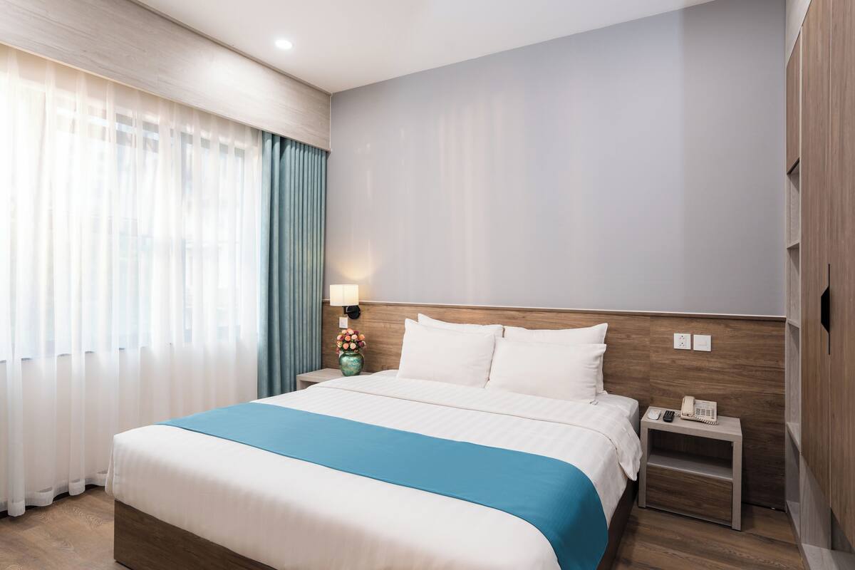 A hotel room with a large bed, a nightstand with a lamp, and a wooden headboard.