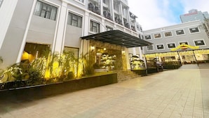 A multi-story hotel with a prominent sign, a covered entrance, and a well-maintained outdoor area with plants. - Capital Garden Hotel (Hanoi)