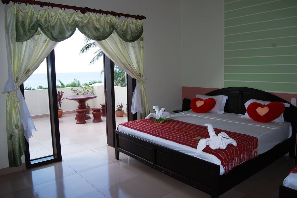 Ein Hotelzimmer mit Bett, einem Balkon mit Topfpflanzen und Blick aufs Meer.
