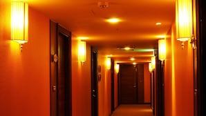 A hotel hallway with doors on both sides, illuminated by wall-mounted lamps. - Eastern Star Hotel (Taipei)