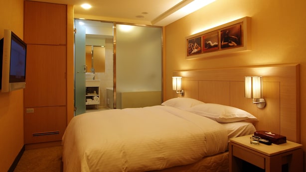 A hotel room with a bed, bedside table, TV, and a bathroom visible through an open door. - Eastern Star Hotel (Taipei)