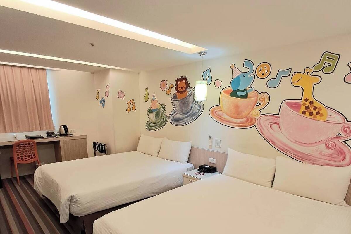 Une chambre d’hôtel avec deux lits, un bureau, une chaise et une fresque murale représentant des notes de musique et un lion.