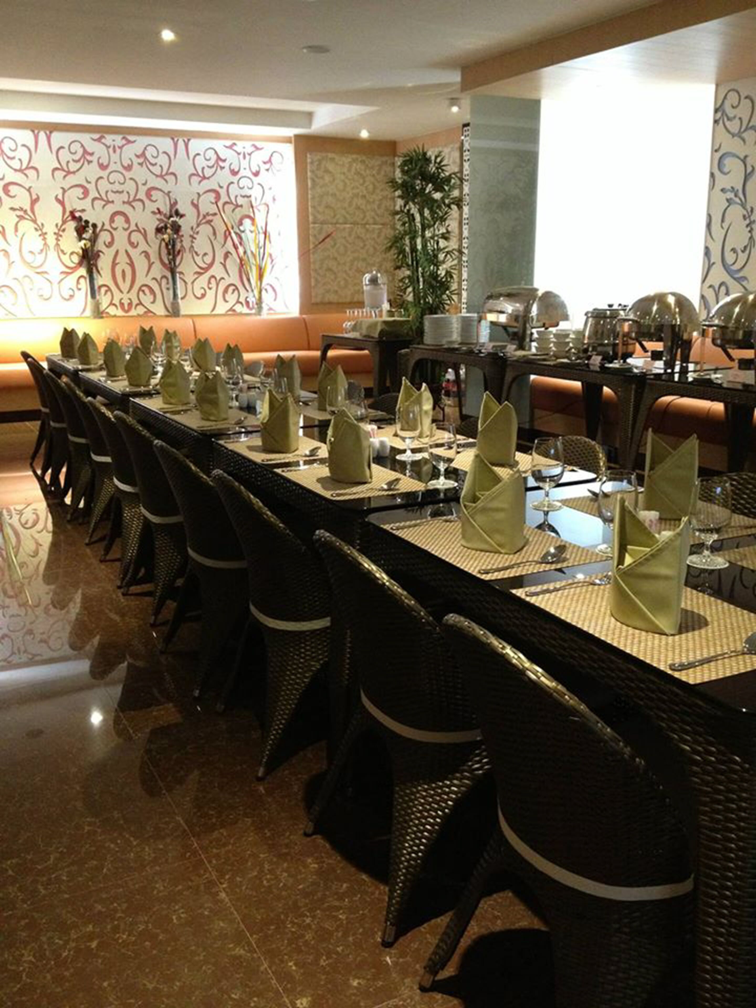 Comedor con una larga mesa dispuesta para varios comensales, rodeada de sillas de mimbre.