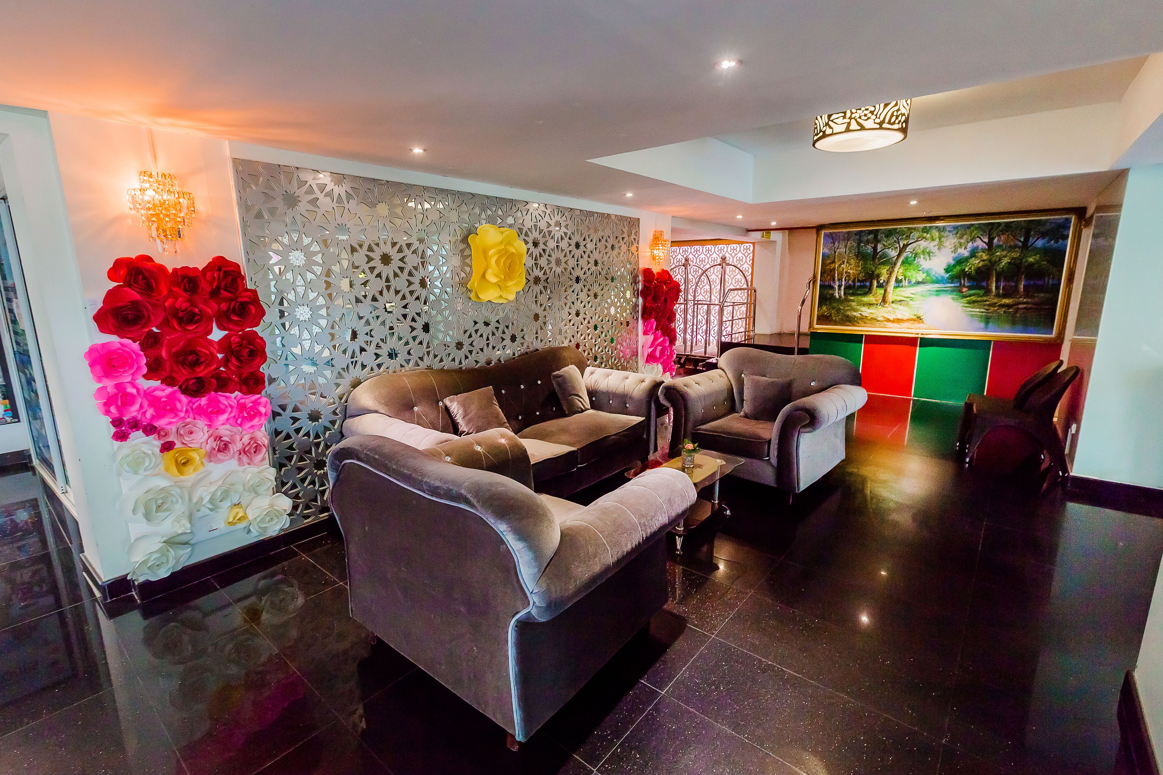 A modern lobby with a sofa, chairs, decorative wall panels, and a large painting.