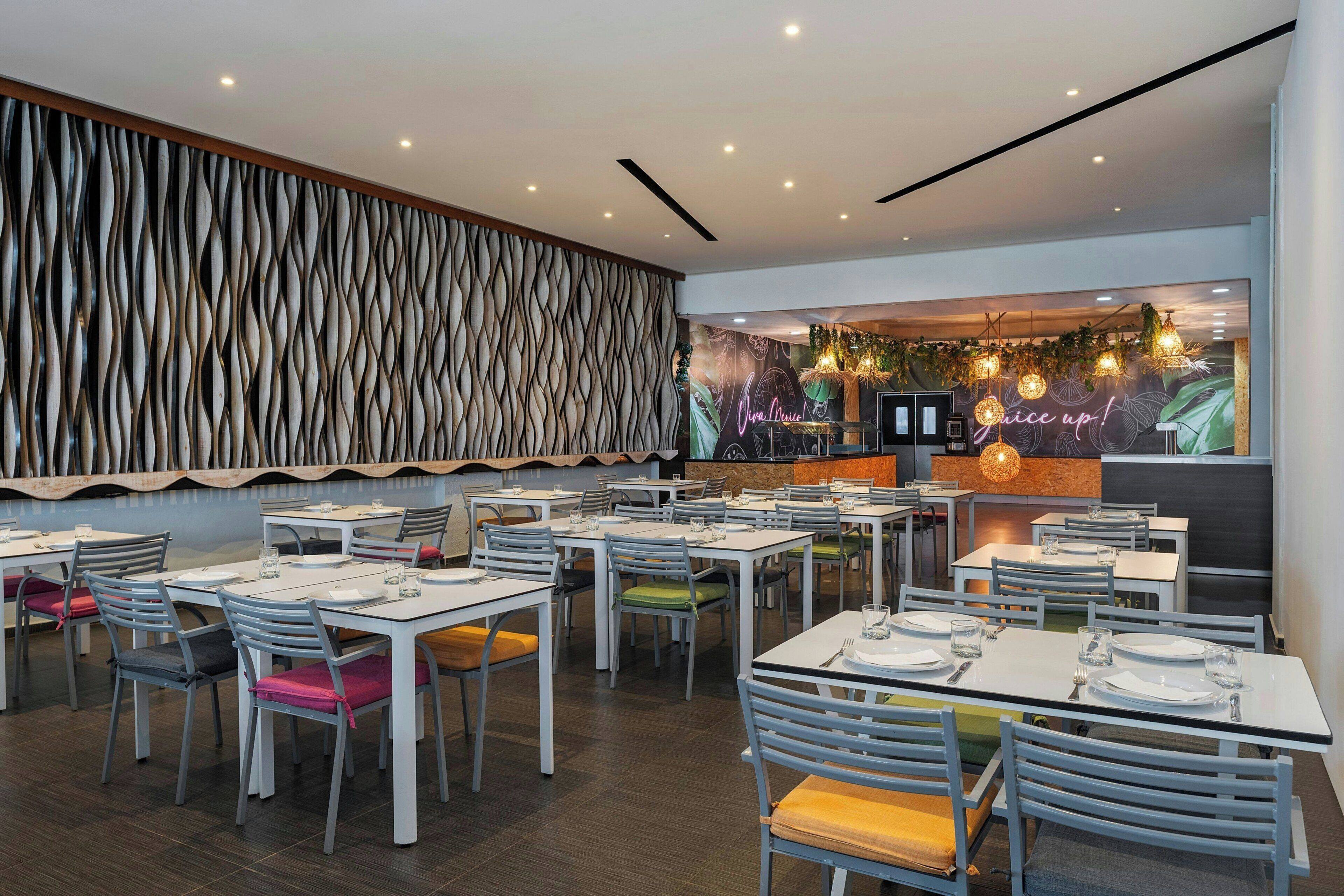 A modern restaurant interior with white tables and chairs, a wooden textured wall, and a neon sign.