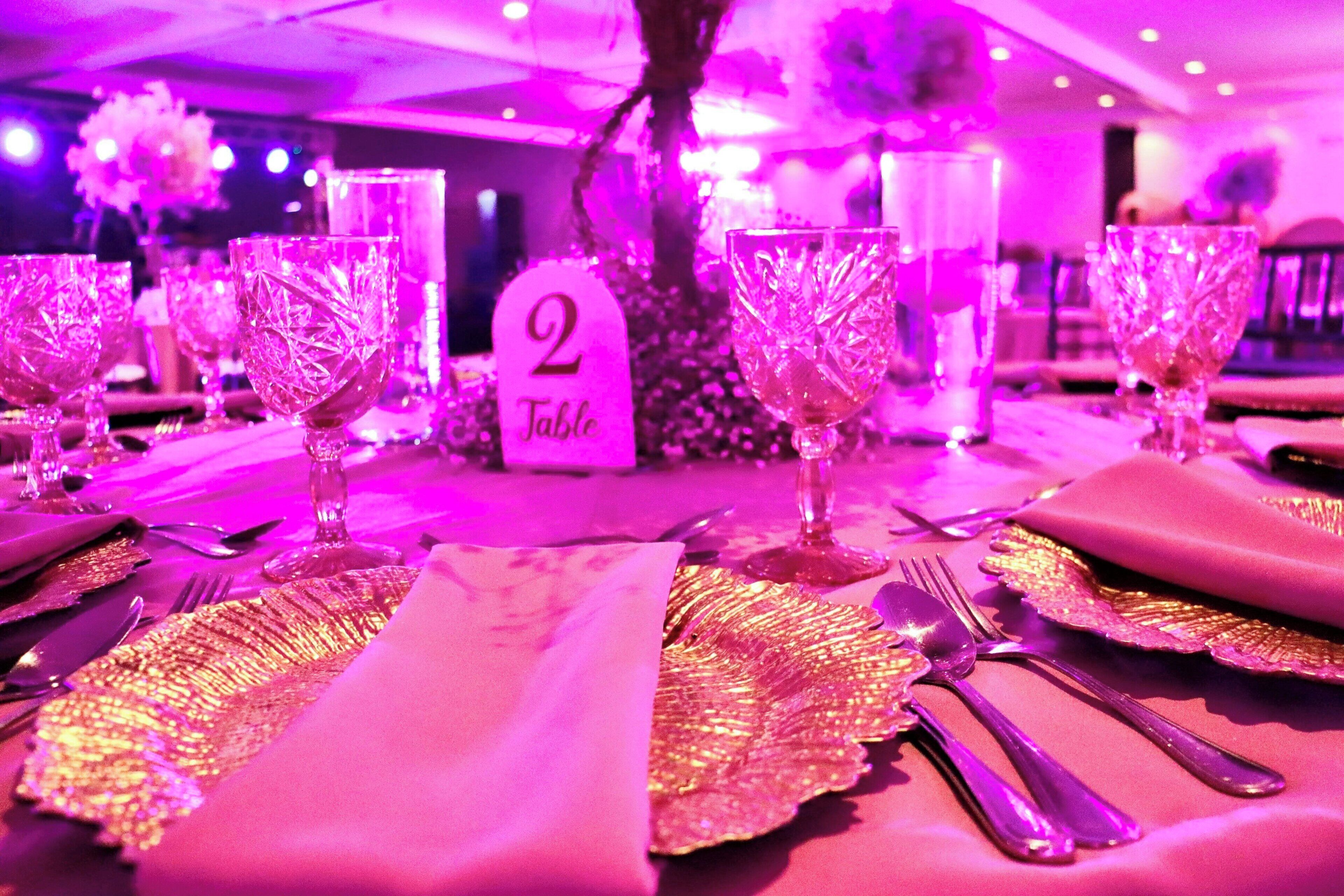 A table set with crystal glassware, gold table runners, and a sign indicating 'Table 2'.