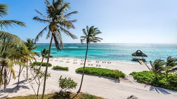 Pantai di sekitar, pasir putih, kursi berjemur, dan payung pantai