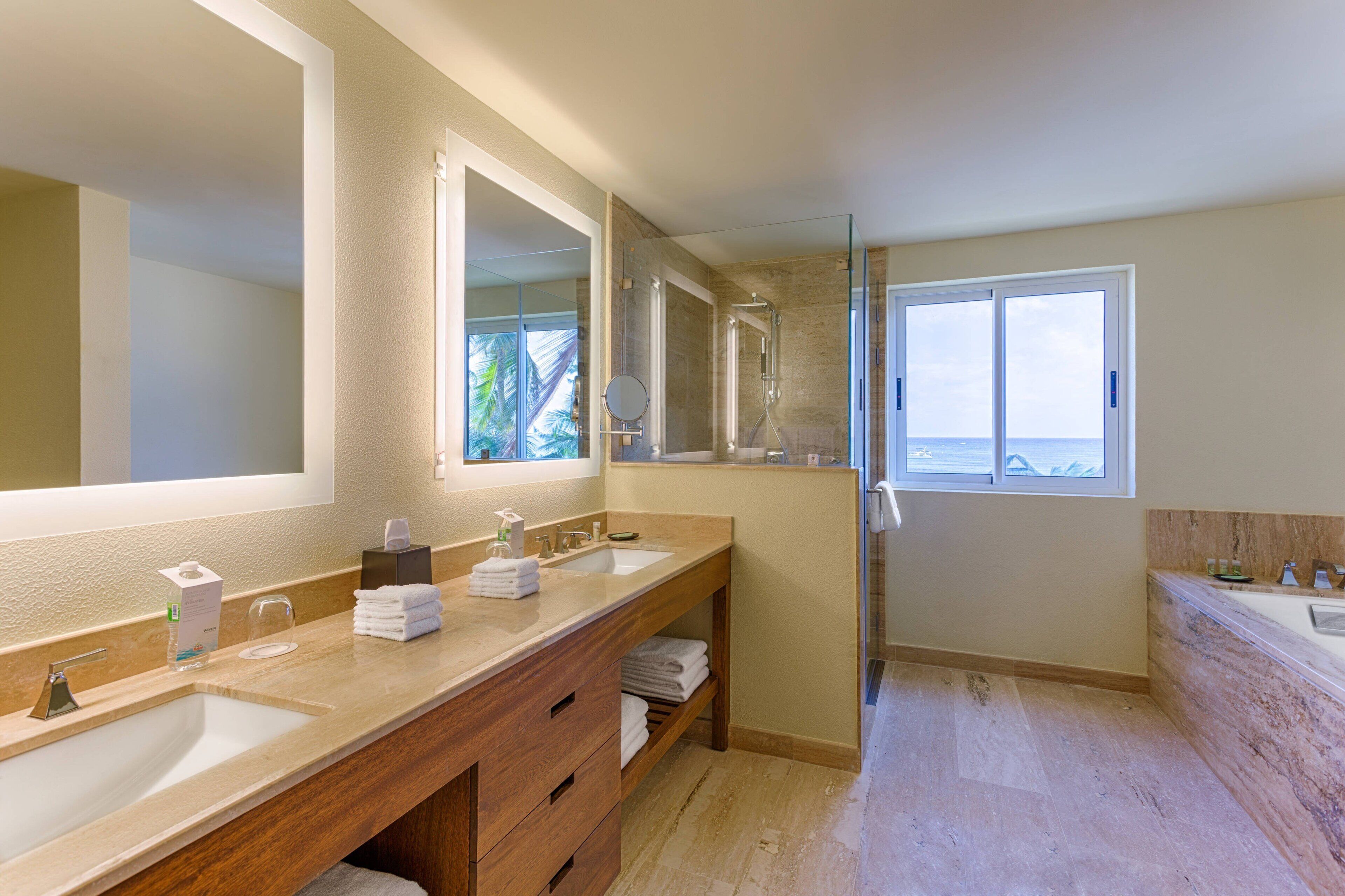 Une salle de bain moderne avec deux lavabos, un grand miroir et une douche à l’italienne.