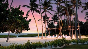 Un décor de plage avec des palmiers, des guirlandes lumineuses et des jardinières blanches.