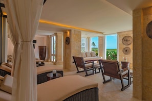 A spacious lounge area with a sofa, chairs, and a table, featuring a view of the outdoors.