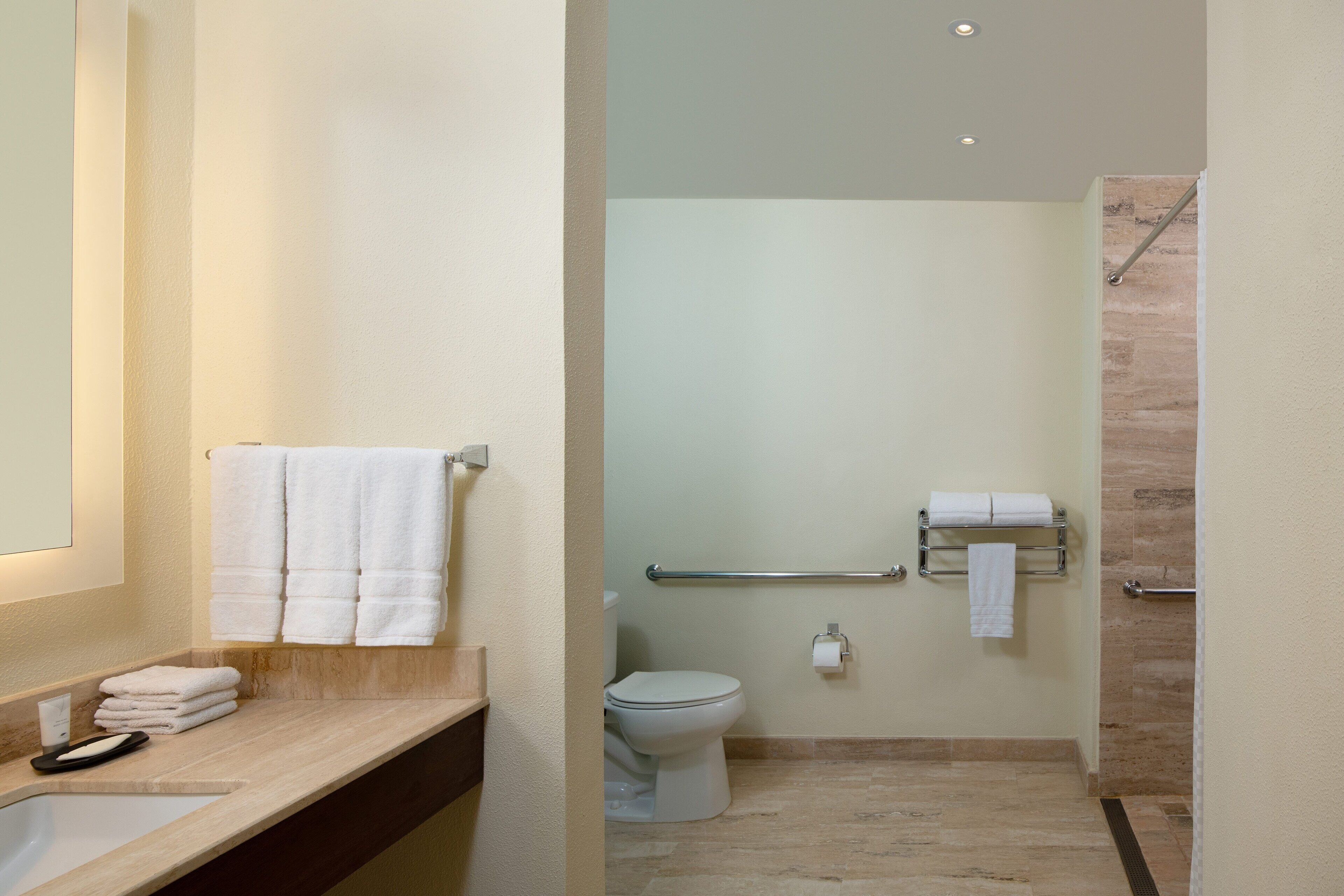 A bathroom with a sink, mirror, and two towel racks.