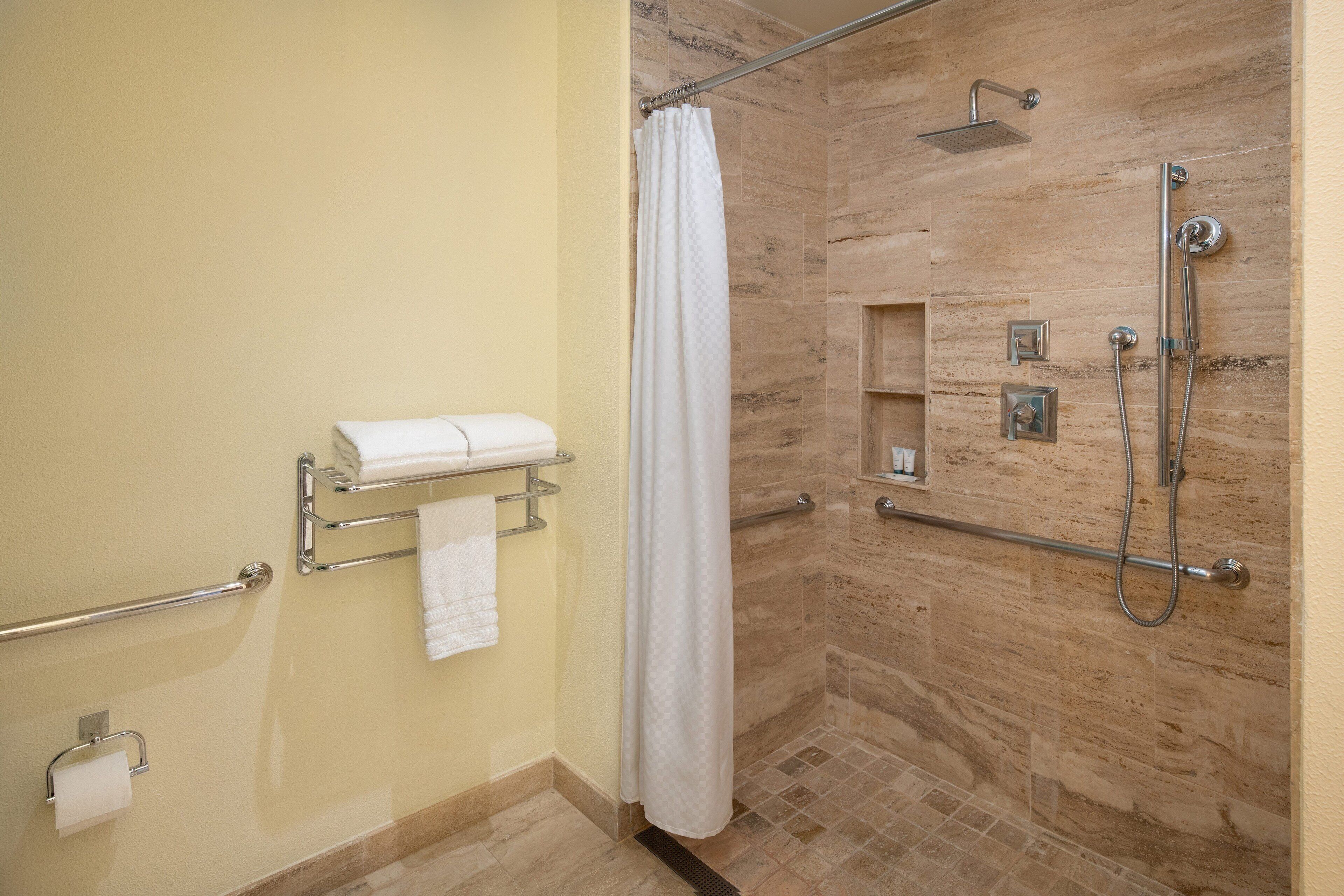 A shower area with a glass door, a towel rack with a towel, and a showerhead.