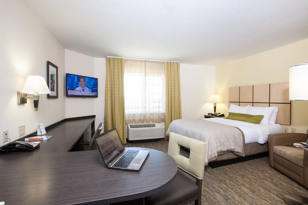 Habitación de hotel con escritorio, computadora portátil, cama y dos sillas.