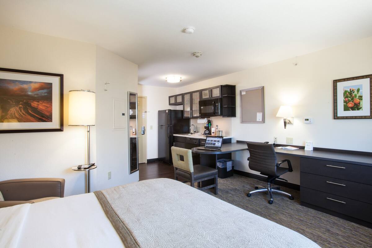 Habitación de hotel con cama, escritorio, kitchenette y una silla.