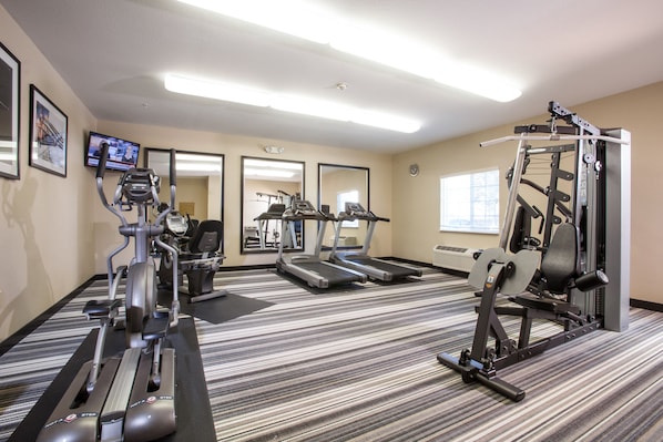 Un gimnasio con cintas de correr, elípticas y equipo de pesas.