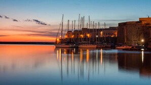 A harbor at dusk with boats docked and a building with a stone wall. - Bed & Breakfast Aria di Mare (Gallipoli)