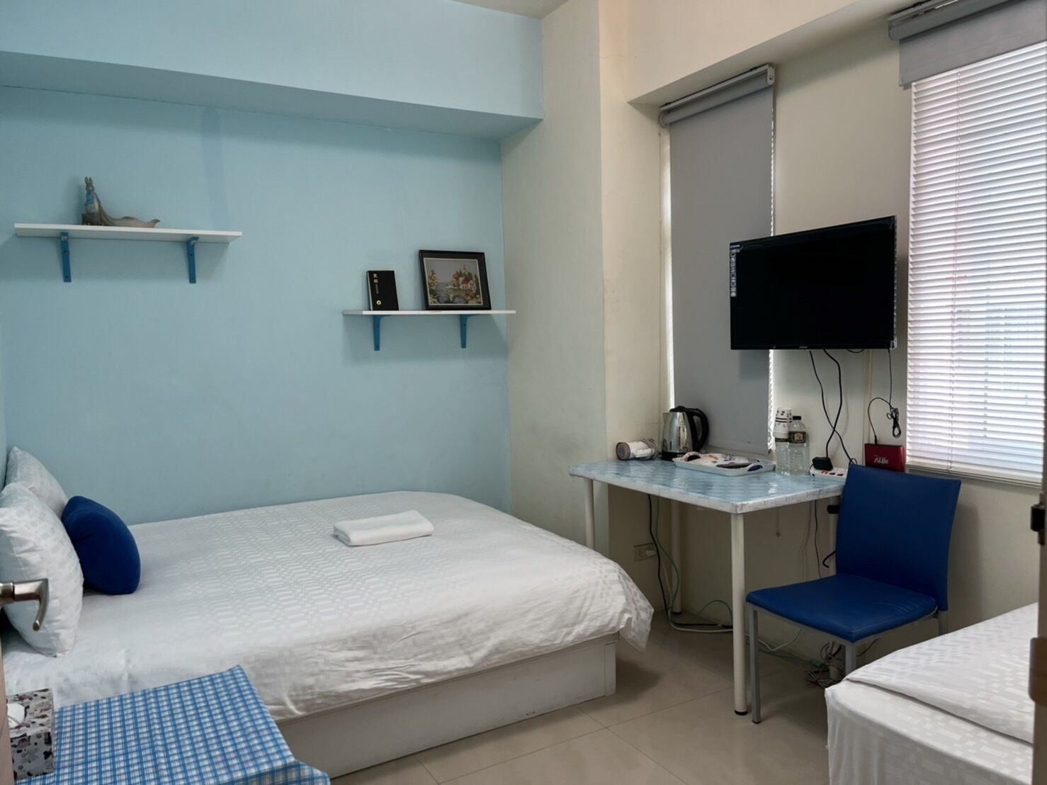 A bedroom with a bed, a desk, a chair, and a television.