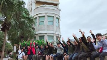 A group of people sitting on a concrete ledge with a modern building in the background.