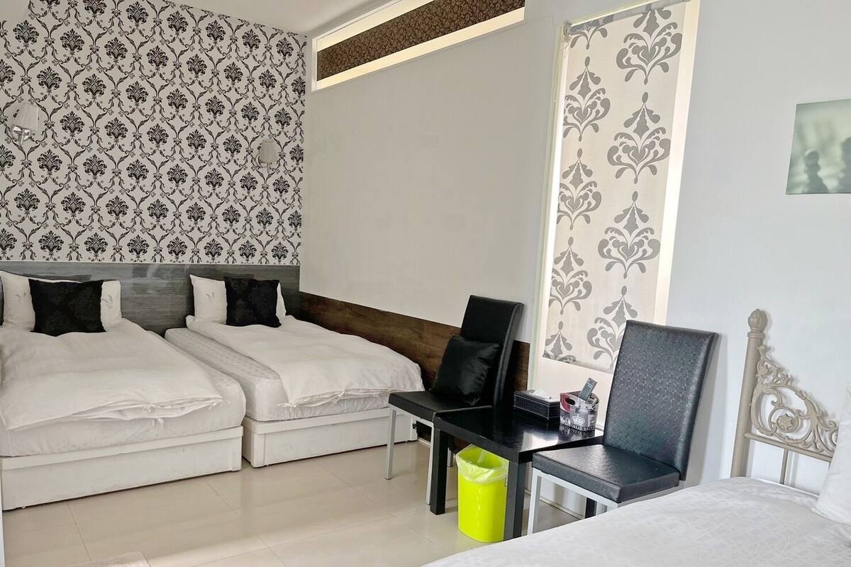 A hotel room with two beds, a desk, and a chair.