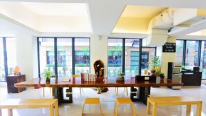 Un comedor moderno con una larga mesa de madera, cuatro taburetes de madera y un perro acostado en el suelo.