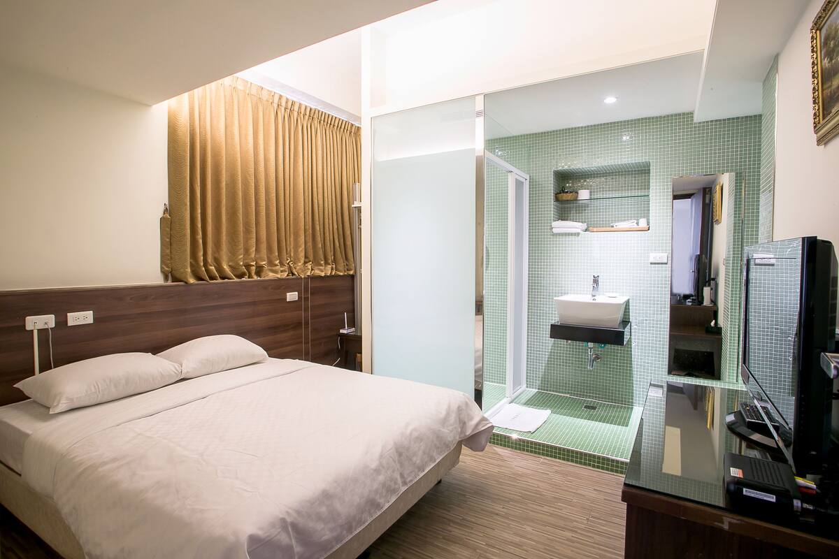 A hotel room with a bed, a bathroom with a sink, and a television.