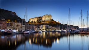 A historic fortified building with a moat, surrounded by a marina with boats. - Casa Murina Hôtel Demeure Ecologique (Serra-di-Ferro)
