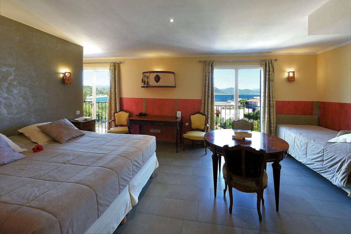 A hotel room with two beds, a dining table, and a desk.