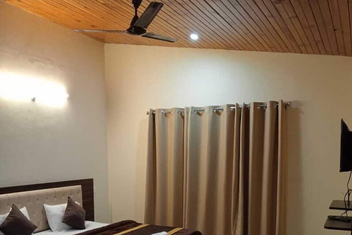 A hotel room with a bed, a sofa, a ceiling fan, and curtains.