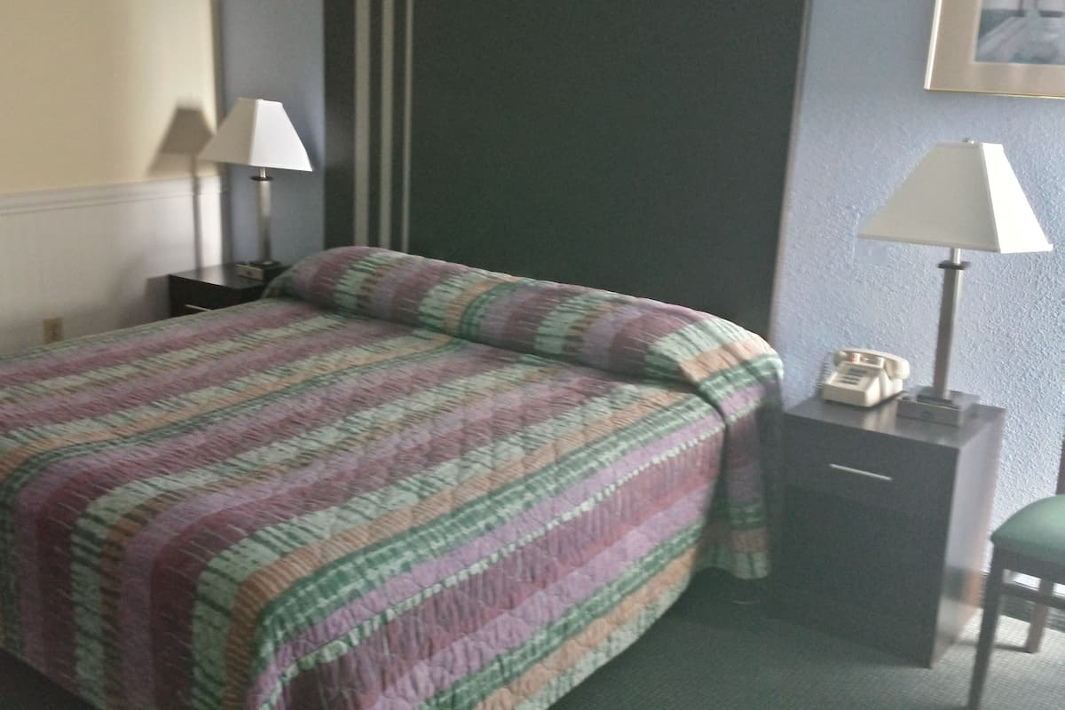 A hotel room with a bed, two bedside tables, a lamp on each table, and a telephone on one of the tables.