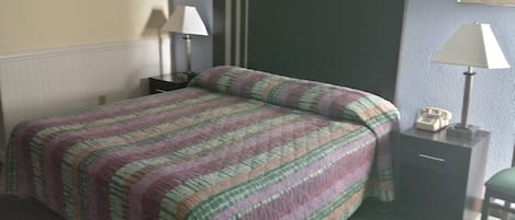 A hotel room with a bed, two bedside tables, a lamp on each table, and a telephone on one of the tables.