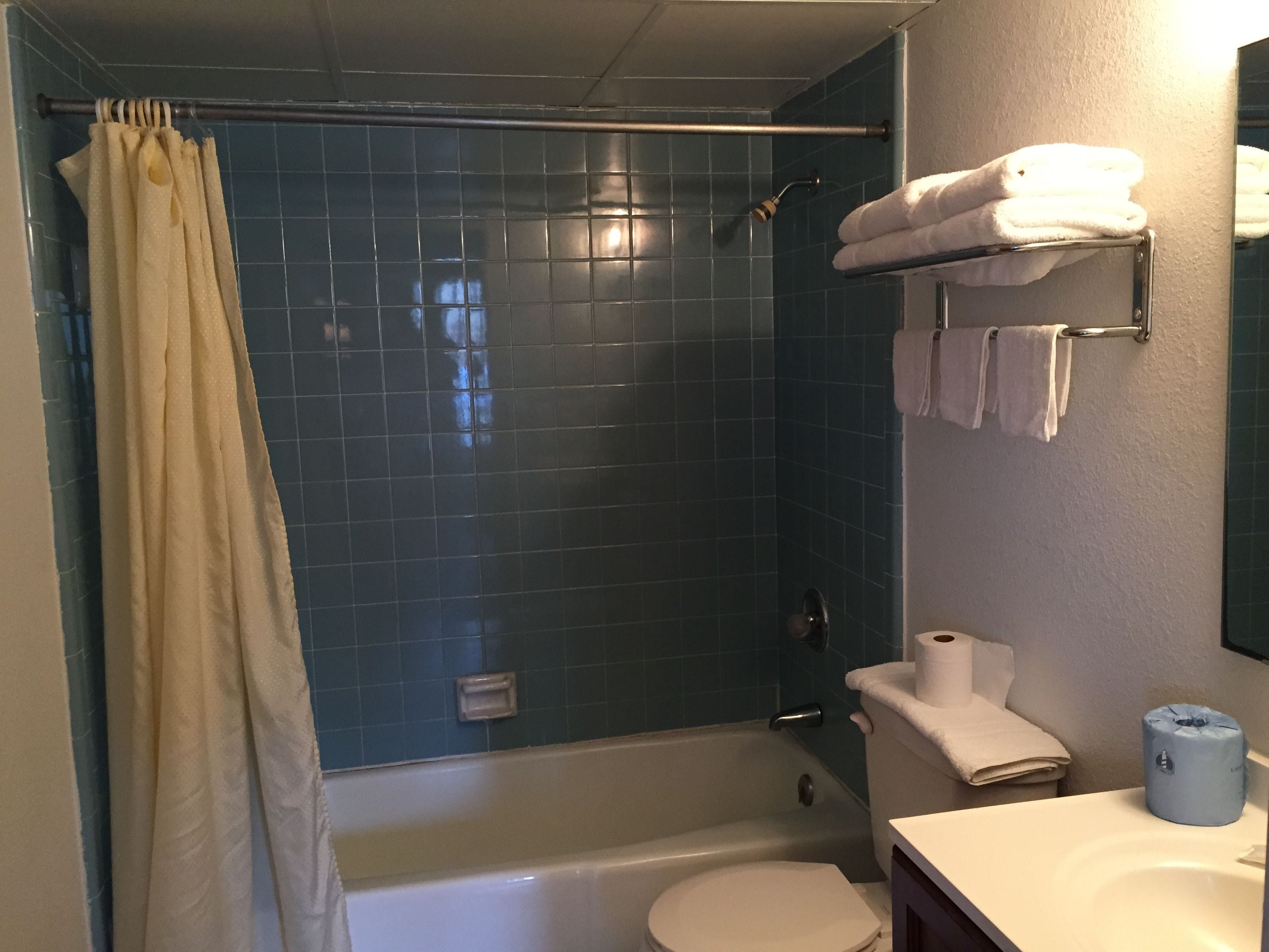 Et badeværelse med bruser, toilet og vask.