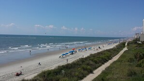 A beach with umbrellas, people, and a clear sky. - Bermuda Sands on the Boardwalk (Myrtle Beach)
