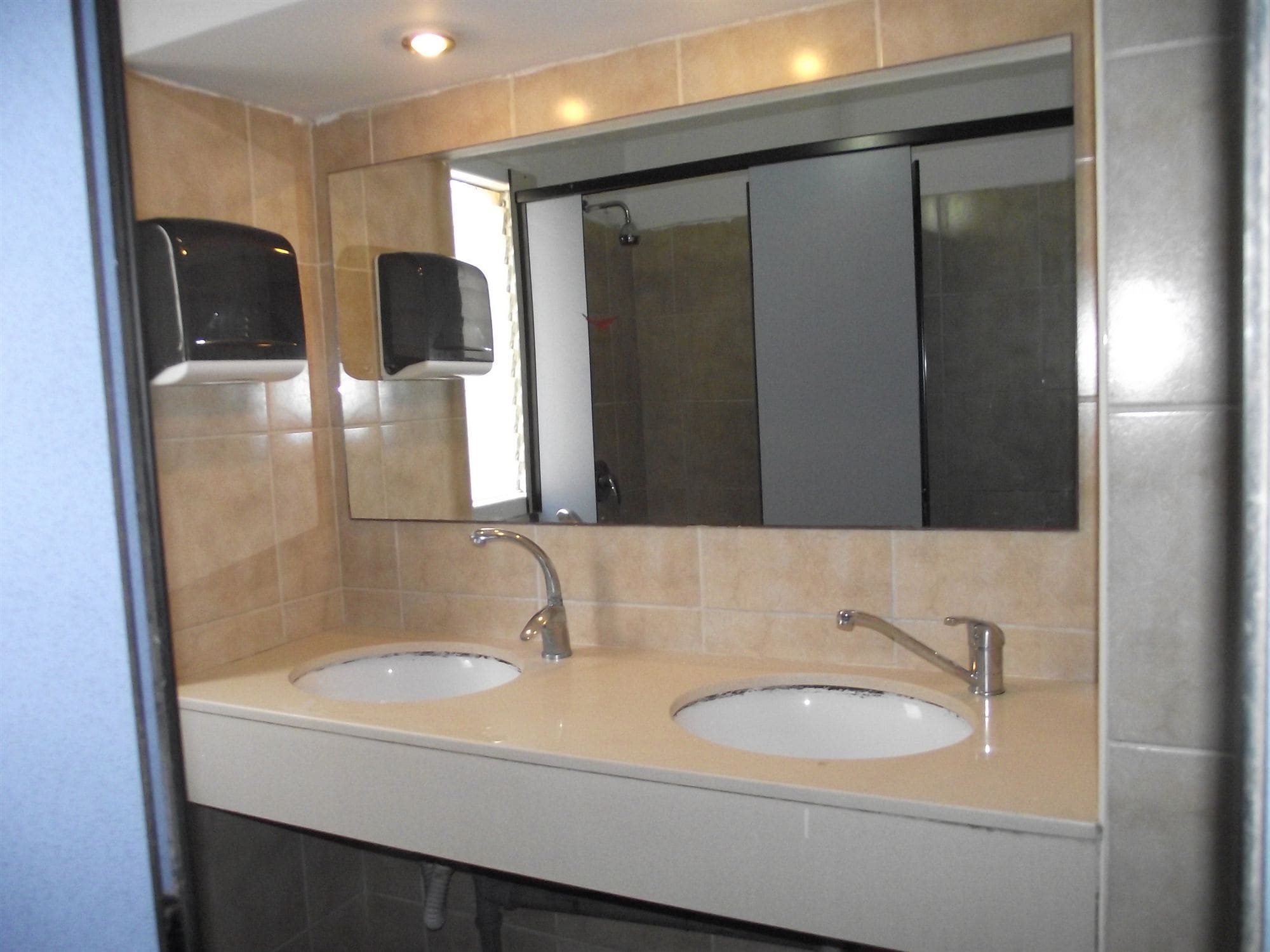 Casa de banho com duas pias, um espelho e um dispensador de sabonete.