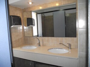 Une salle de bain avec deux lavabos, un miroir et un distributeur de savon.