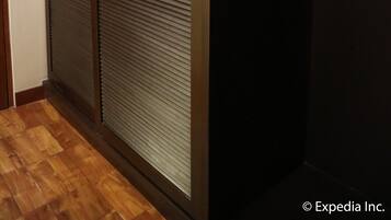 Un pasillo con piso de madera y una puerta corrediza con persianas horizontales.