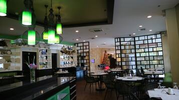 Interior de un restaurante con barra, mesas de comedor y un árbol de Navidad.