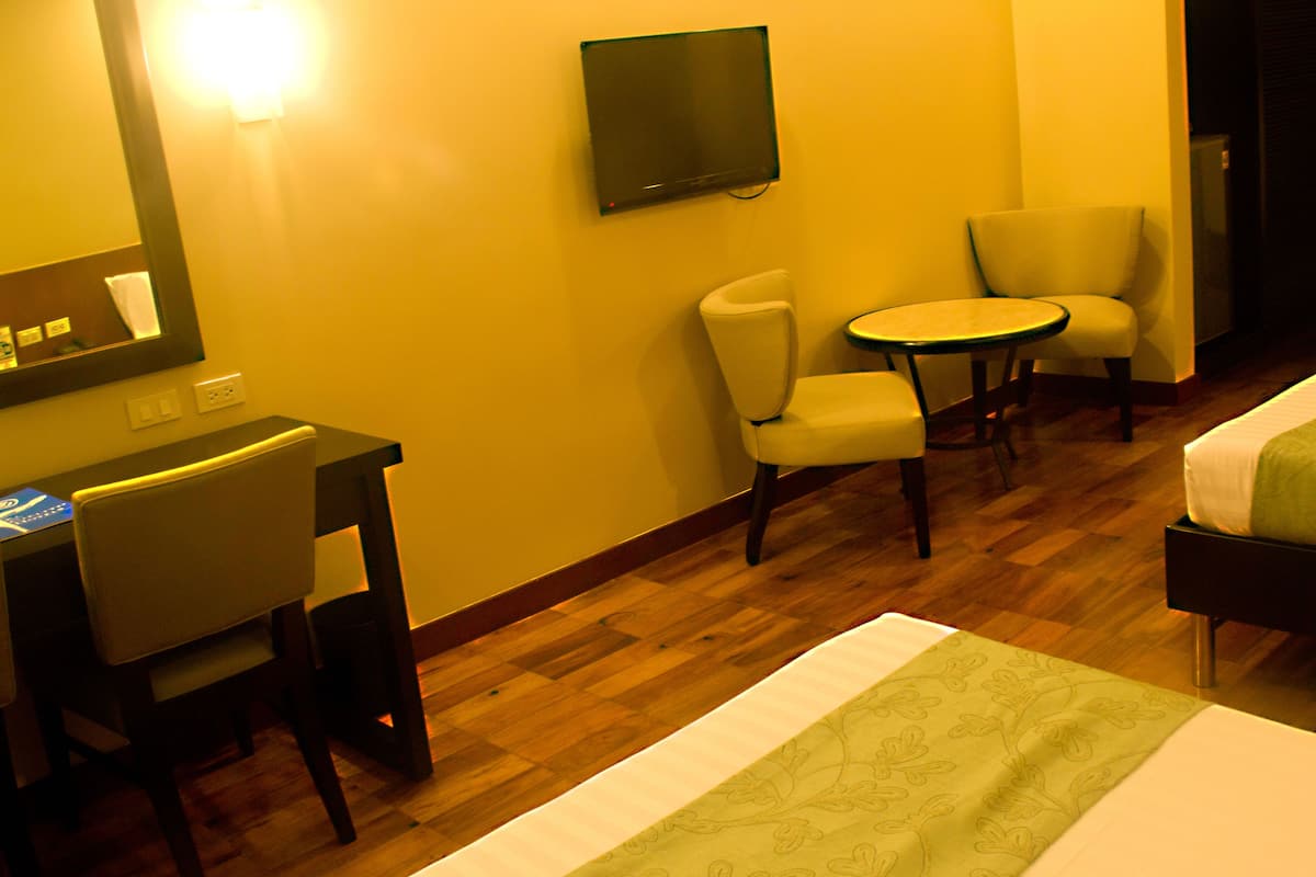 A hotel room with a bed, a desk with a chair, a small round table, and two armchairs.