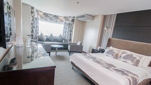 A hotel room with a large bed, a desk, a chair, a small table, and a sofa. - El Cielito Hotel - Sta. Rosa (Santa Rosa)
