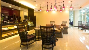 A modern cafe with wicker chairs, a counter with baked goods, and pendant lighting. - El Cielito Hotel - Sta. Rosa (Santa Rosa)