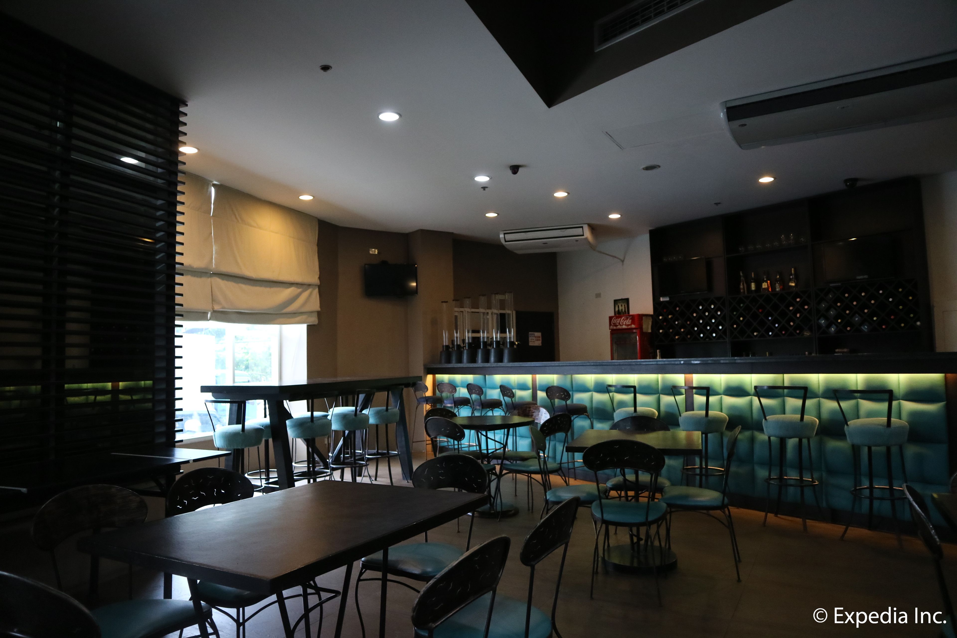 A restaurant with a bar area, tables, and chairs.