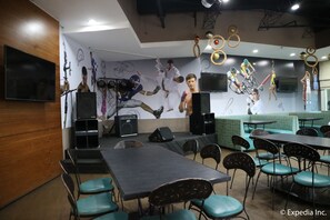 A dining area with tables and chairs, a stage with speakers, and a mural on the wall.