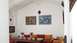 A room with a wooden table, two sofas, and two paintings on the wall. - Riad Arous Chamel (Tangier)